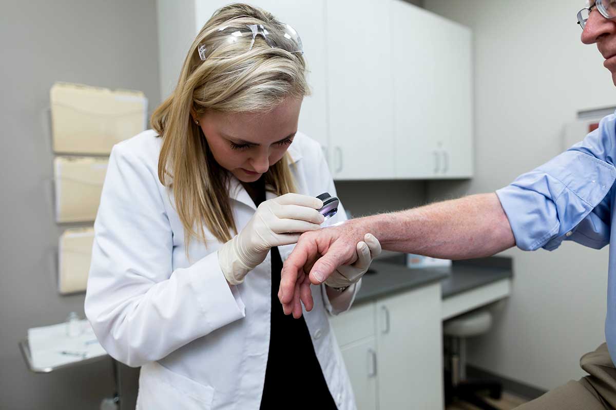 A doctor analyzing an older patient's hand for any abnormalities.